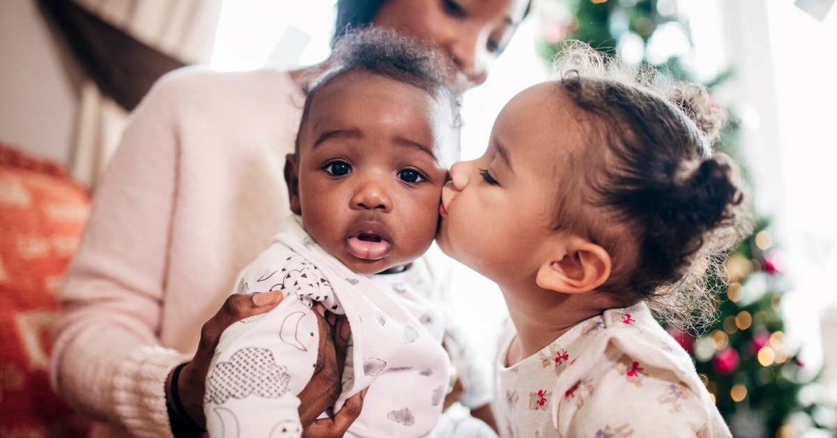 child kisses baby on the cheek