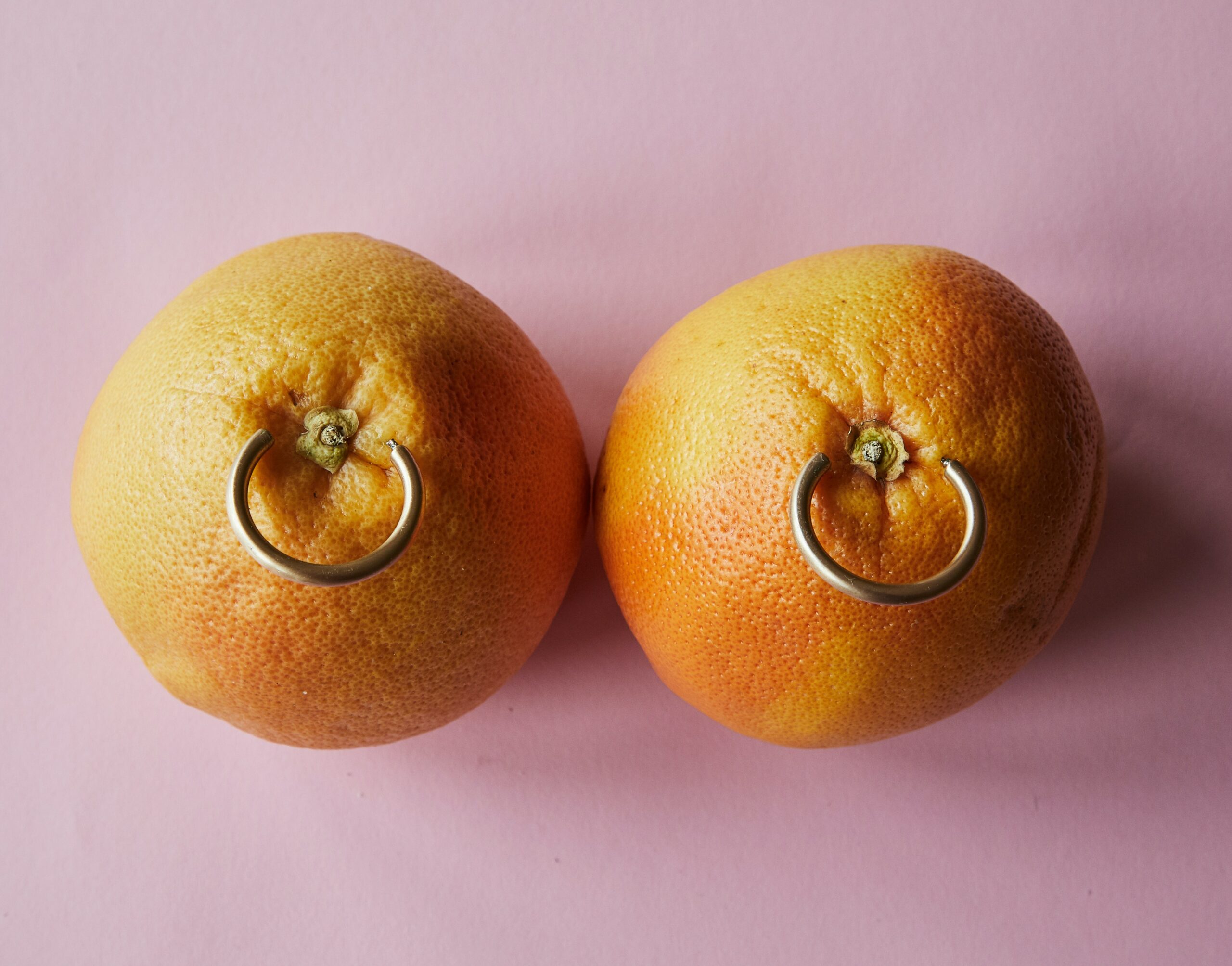 Two oranges with rings pierced through them