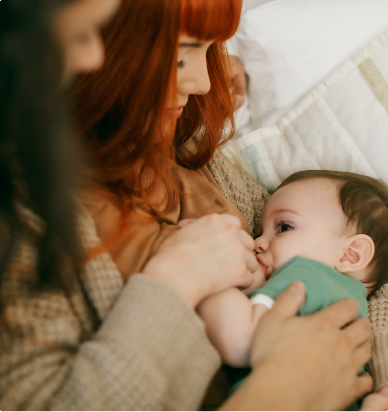 A mother breastfeeds her baby while an IBCLC provides guidance.