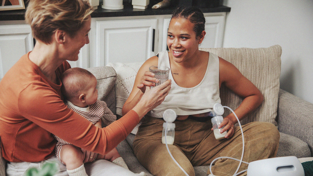 Lactation consultant handing a pumping parent a glass of water