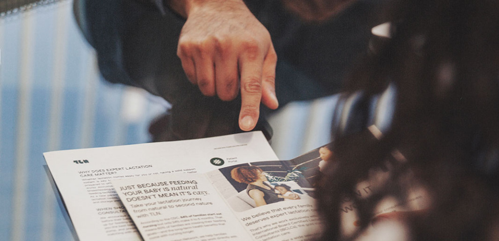 A parent reviews insurance information in a trifold while being helped by a benefits specialist.